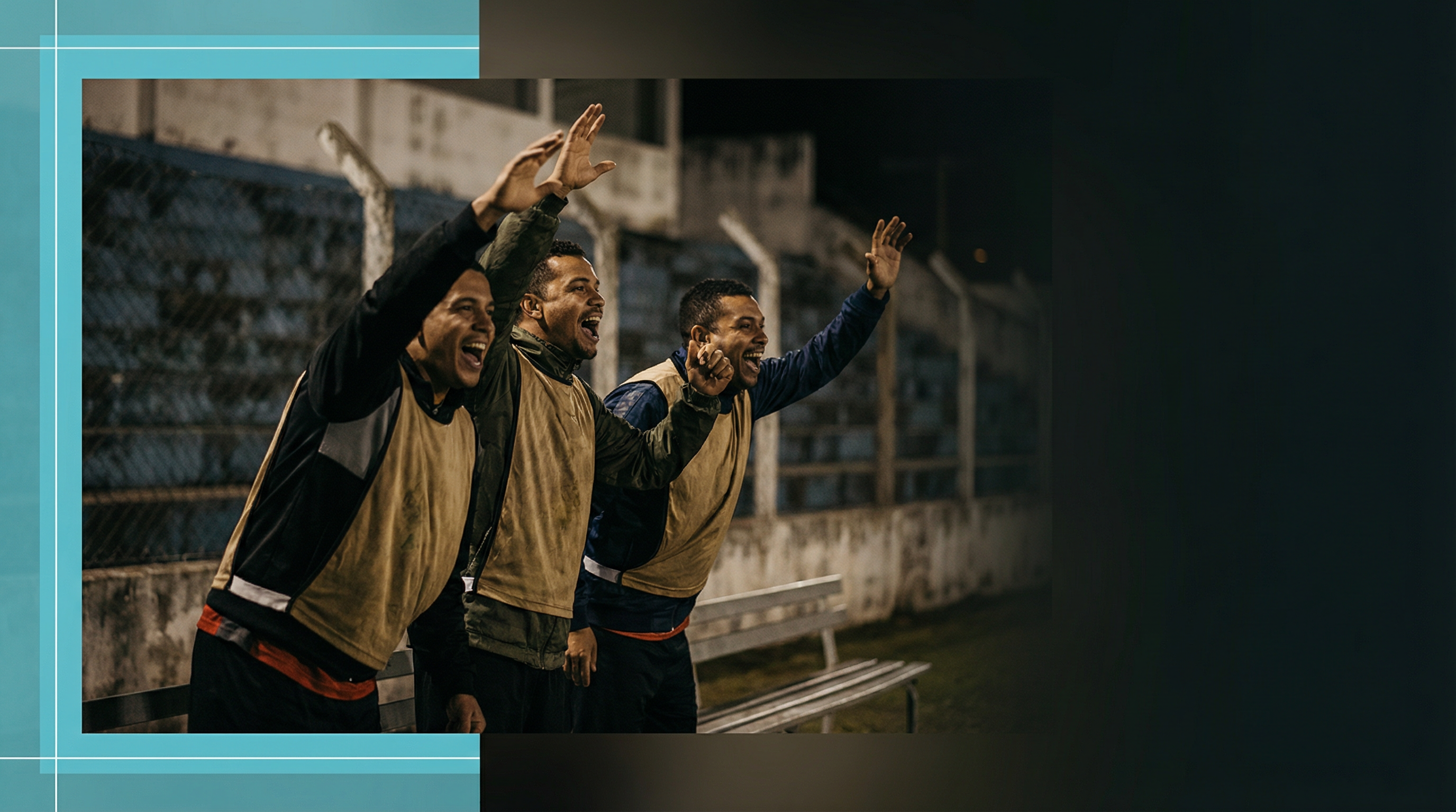 Três torcedores animados celebram em um campo de futebol à noite, vestindo coletes e sorrindo, com um fundo de arquibancada.