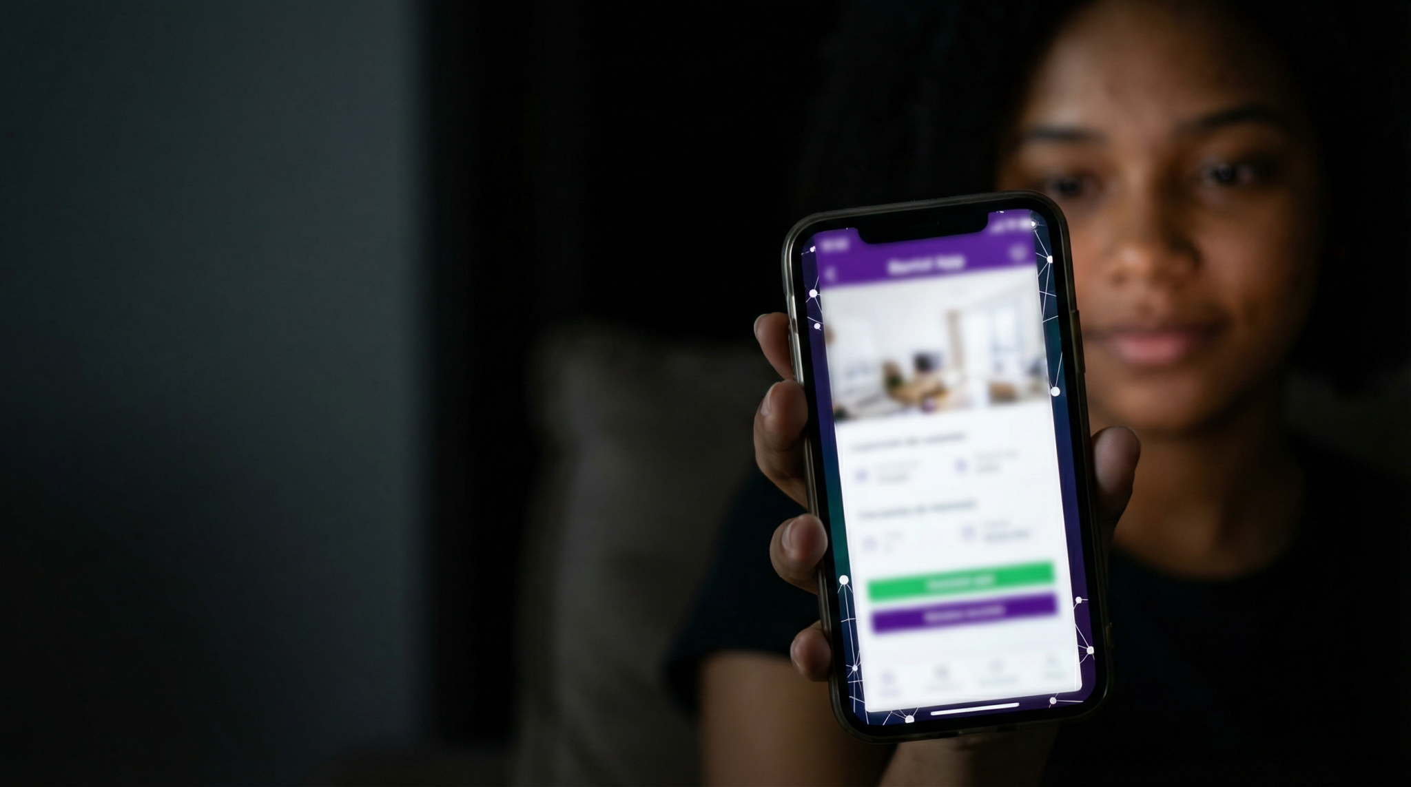 Pessoa segurando um smartphone que exibe um aplicativo de locação com detalhes de imóvel, luz suave ao fundo.